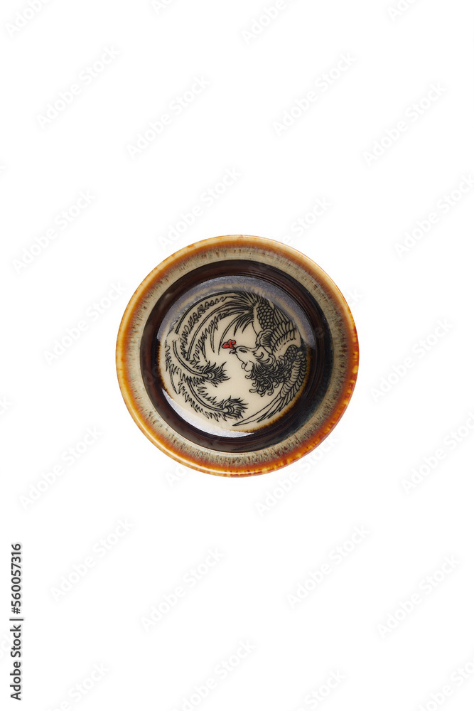 Detailed shot of a fujian ceramic hand painted cup decorated with a picture on the bottom. The designer temmoku glazed handmade bowl in chinese style is located on the light background.
