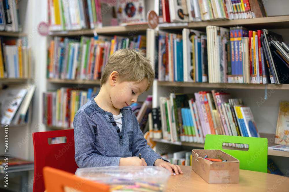 Adorable little boy, sitting in library, reading book and choosing what to lend, kid in book store. Adorable little boy, sitting in library, reading book and choosing what to lend, kid in book store.