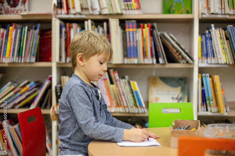 Adorable little boy, sitting in library, reading book and choosing what to lend, kid in book store. Adorable little boy, sitting in library, reading book and choosing what to lend, kid in book store.