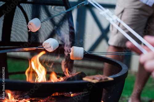 Midsection of man roasting marshmallow on campfire at yard photo