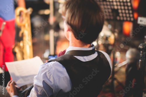 Orchestra jazz musician during performance, rehearsal sound recording, saxophonist player holding musical notes on paper sheet, before the concert, musicians ready to start the concert on a stage