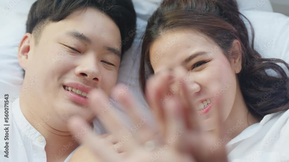Top view young couple asia people lying down talk on bed relax smile hold hands look at ring on finger. Sweet happy lover asian man woman fall in true love new family life begin just married moment. Top view young couple asia people lying down talk on bed relax smile hold hands look at ring on finger. Sweet happy lover asian man woman fall in true love new family life begin just married moment.