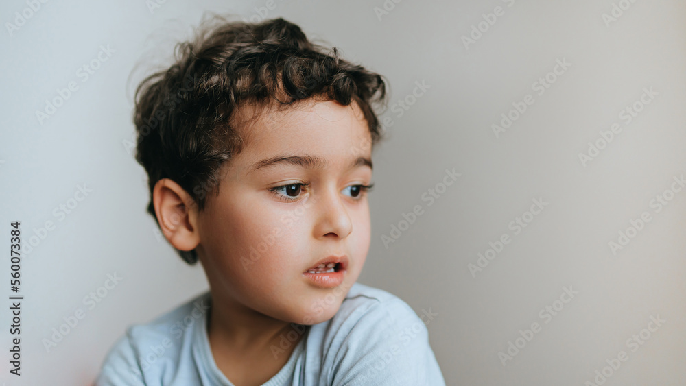 Handsome caucasian curly baby boy sitting at home wants to play outside