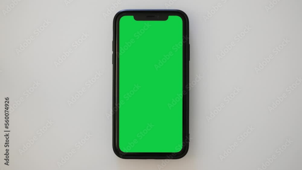 Single Tapping on a Green Screen Smartphone on a White Table Single Tapping on a Green Screen Smartphone on a White Table