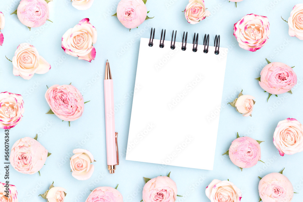 Empty notepad mockup. Stationery and pink rose flowers on a blue background.
