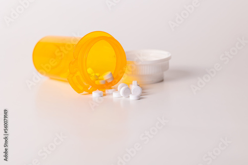 white pills coming out of prescription pill bottle isolated on white background with room for copy or print.