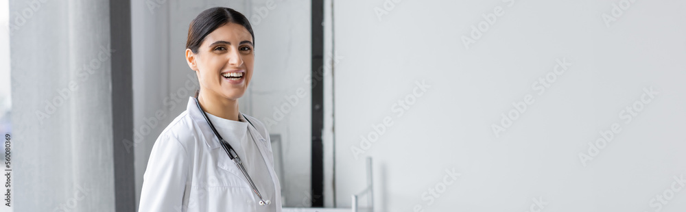 Positive doctor with stethoscope looking at camera n clinic, banner. Positive doctor with stethoscope looking at camera n clinic, banner.