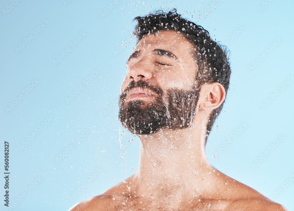 Man shower, cleaning face and studio for self care wellness, relax and beauty by blue background. Model, skincare and water drop on facial, beard and self love for health, body or clean by backdrop