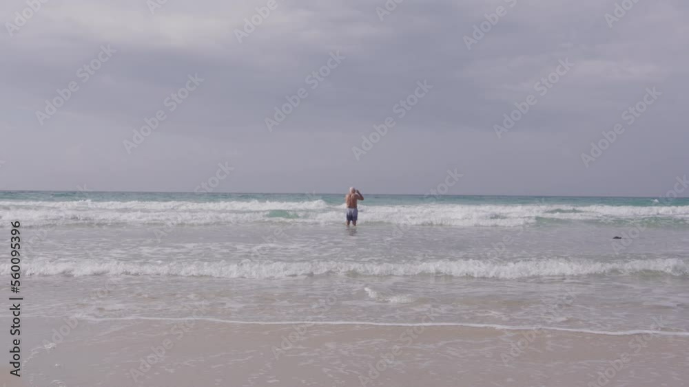 Senior man is going to swim in the ocean Senior man is going to swim in the ocean