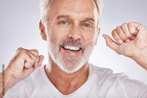 Face, dental floss and senior man in studio isolated on a gray background. Portrait, cleaning and elderly male model with product flossing teeth for oral wellness, tooth care and healthy gum hygiene