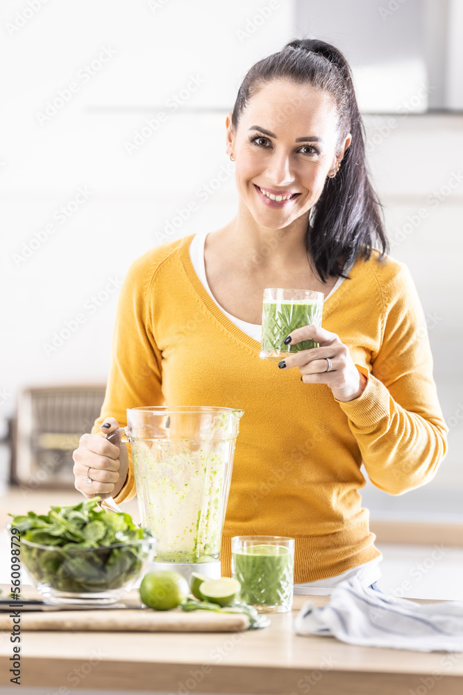 Smiling woman holding a glass of spinach green smoothie. Smiling woman holding a glass of spinach green smoothie.