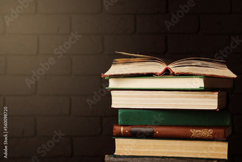 Stack of old hardcover books near brick wall, space for text