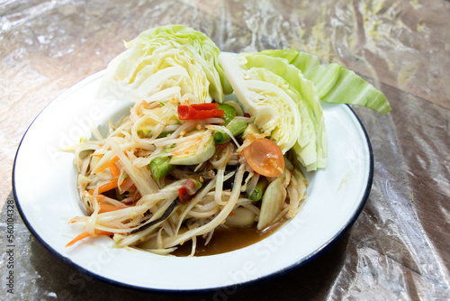 Thai papaya salad (Somtum) in white plate on wooden table
