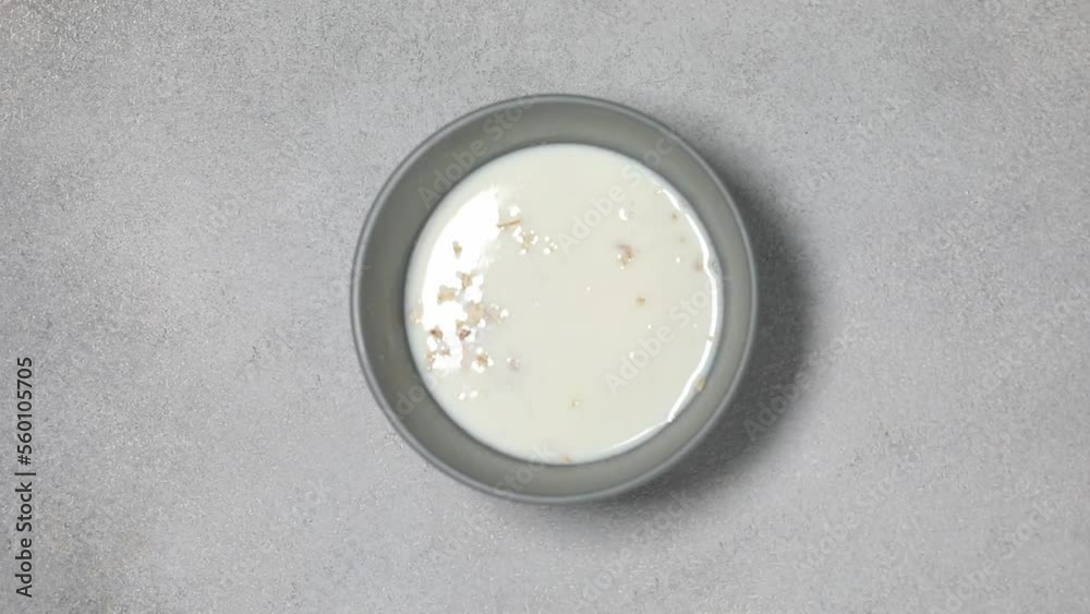 Pouring milk from a bottle into a bowl with cornflakes cereals. Bowl with corn cereals and milk isolated on a grey background Pouring milk from a bottle into a bowl with cornflakes cereals. Bowl with corn cereals and milk isolated on a grey background