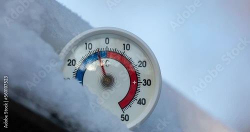 Thermometer with celsius scale in snow demonstrates ambient temperature rising up from minus 6 degrees to zero - spring weather change or global warming concept 4K timelapse