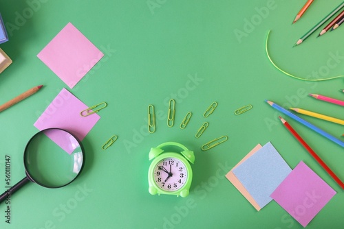 Stationery, alarm clock, books on a background of pastel colors of multi-colored paper, back to school, education, schoolchild study table, copy space, top view
