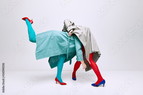 Portrait of two young girls in bright red and blue tights and coat posing over grey studio background. Self-expression. Vivid style, queer, art, fashion photo