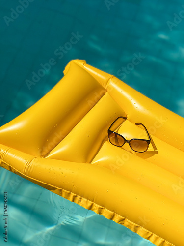Sunglasses on a yellow floater inside a swimming pool in summer time