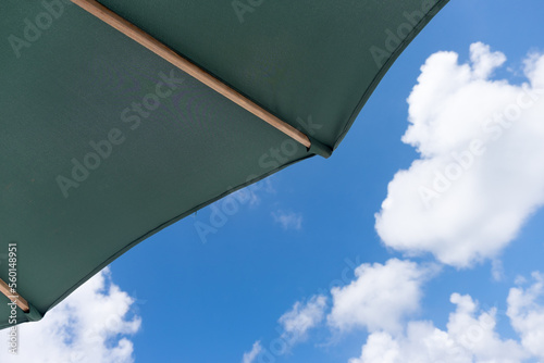 Part of a green umbrella in the foreground, with a partly cloudy sky in the background in the Caribbean