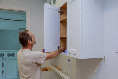 Worker working on door of new kitchen cabinet in new house