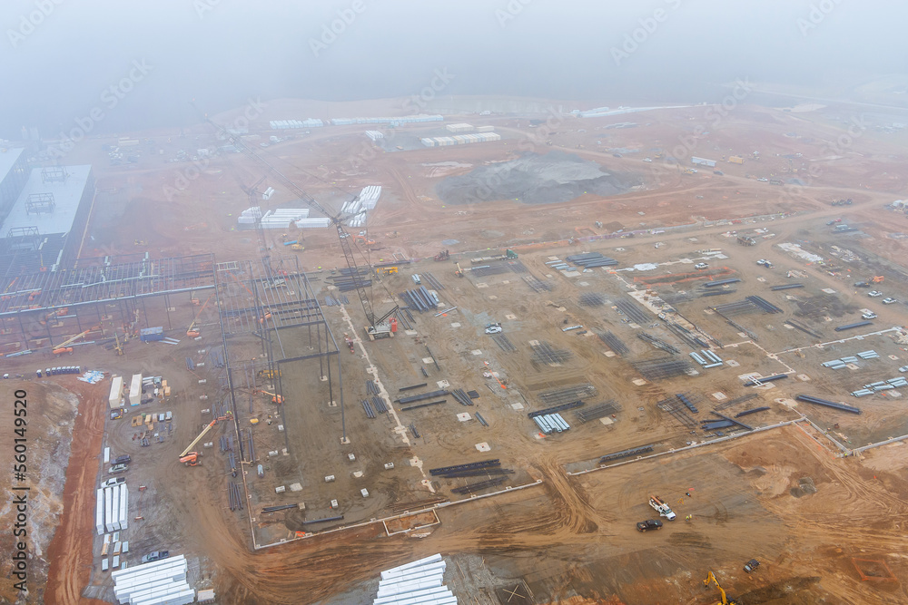 Construction site at dawn in morning when heavy fog is present, when used cranes are being to work to commercial buildings
