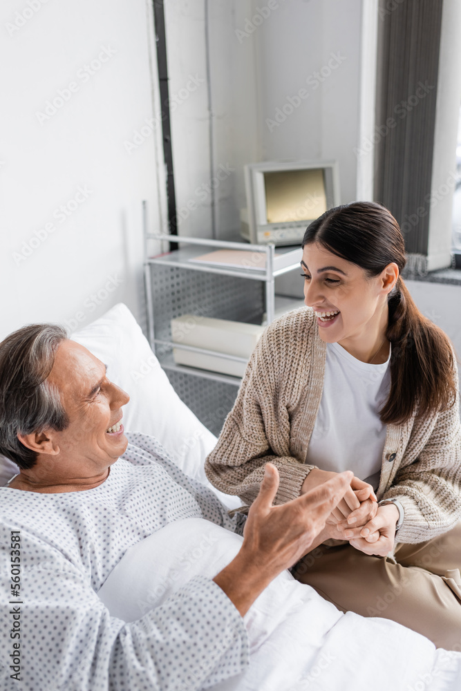 Fototapeta premium Positive man in patient gown talking to daughter in clinic.