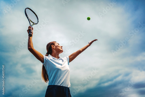 Young handsome tennis player with racket and ball prepares to serve at beginning of game or match.