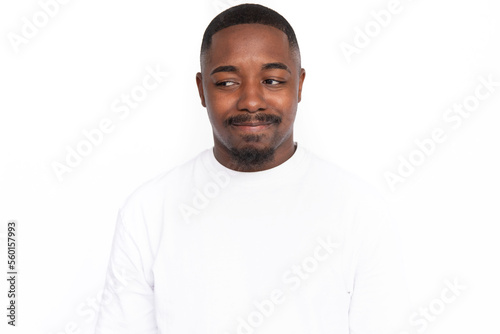 Pensive young man looking away thinking. Male African American model with brown eyes, short haircut and beard in white T-shirt thinking about pleasant memory, dreaming. Thought, dream concept