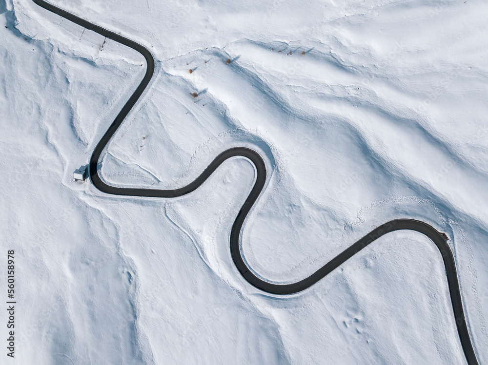 Aerial view of a winding road in the snow in Passo Giau, high alpine pass. Dolomites, Italy. Winter nature background.