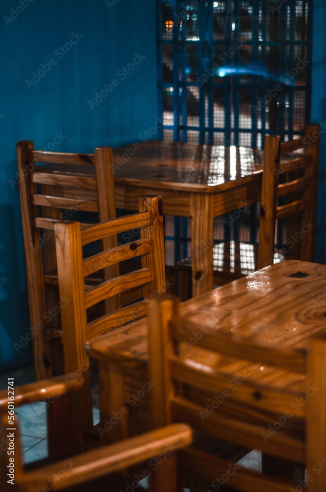 mesas de un pequeño bar con paredes azules y m,muebles de madera