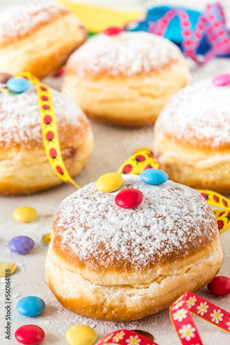 Carnival powdered sugar raised donuts with paper streamers, confetti and chocolate beans, vertical