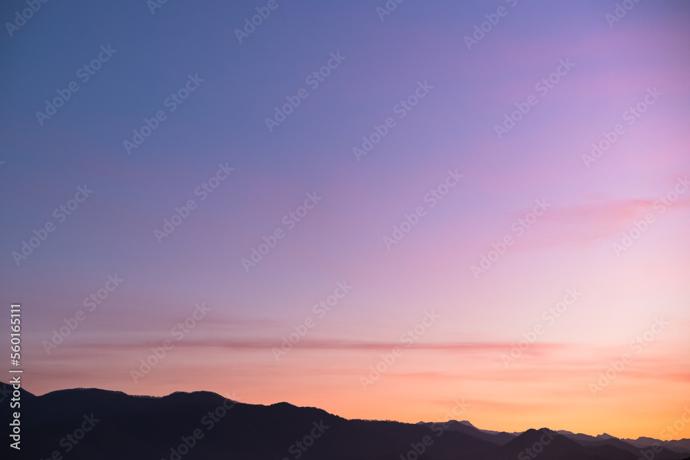 Purple silhouettes of mountains with aerial perspective against the background of the sunset sky. blue purple pink red orange yellow gradient