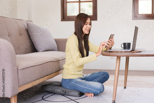 Leisure activity concept, Young woman surfing social media on phone while sitting to relax on floor © Pichsakul