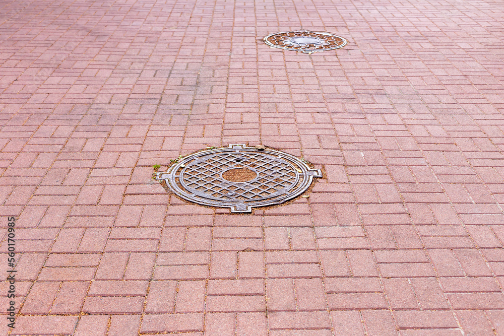 Two iron hatch on the ground among the tiles