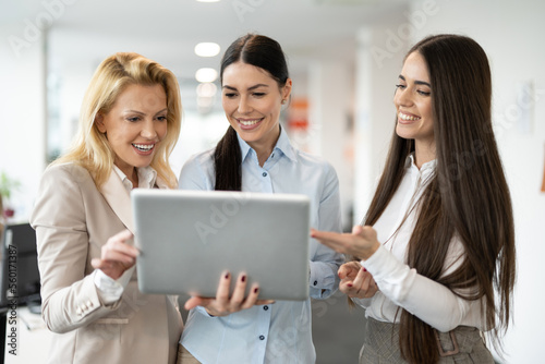 Three beautiful business women using laptop and planning a corporate development concept for the future while standing in the office