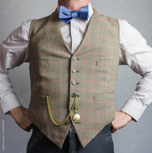 Man in Tweed Waistcoat or Vest and Bow Tie Standing Proudly with Hands on Hips. Vintage Style and Retro Fashion