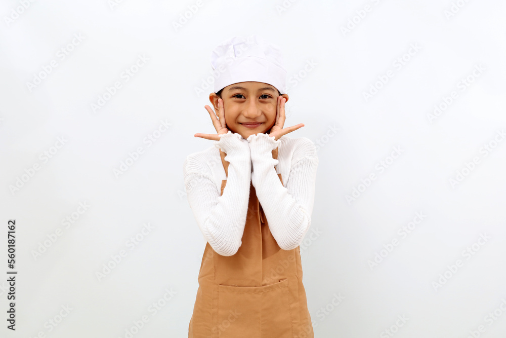 Adorable little girl in chef uniform standing while smiling and looking at the camera. Isolated on white background Adorable little girl in chef uniform standing while smiling and looking at the camera. Isolated on white background