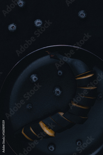 black banana with blueberries on a dark background photo