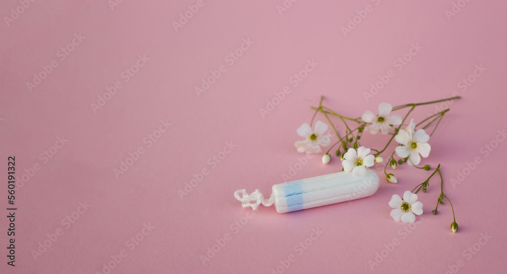 The concept of careful and gentle protection in critical days. Menstruation period concept. Hygienic white tampons for women with flowers on pink backround. The concept of careful and gentle protection in critical days. Menstruation period concept. Hygienic white tampons for women with flowers on pink backround.