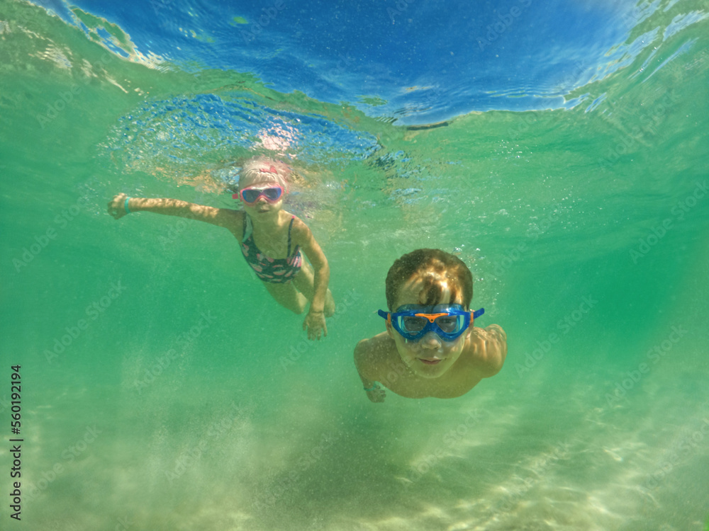 Children dive underwater at the sea on vacation. Swim and snorkeling in the sea.