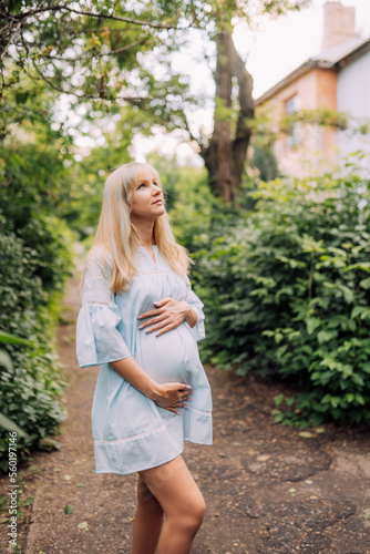Happy pregnant woman in blue dress in garden