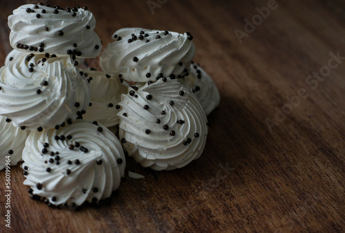 Airy meringue with pieces of chocolate from the top on a white background and wooden surface