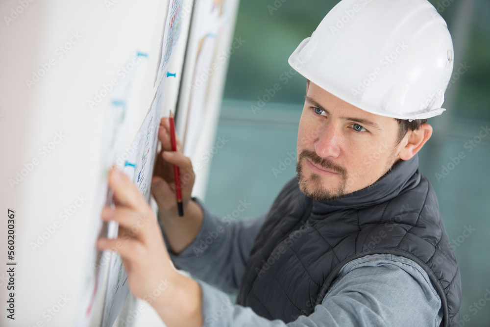 man wearing handhat by notice board man wearing handhat by notice board