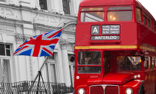 Photo Old vintage double-decker bus with destination Waterloo  in front of the flag of the United Kingdom waving on a white victorian building