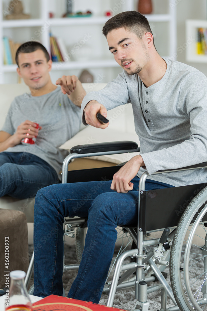 handicap man and friend watching television in living room handicap man and friend watching television in living room