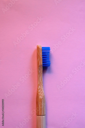 Sustainable wooden toothbrush on pastel pink background. Top view.