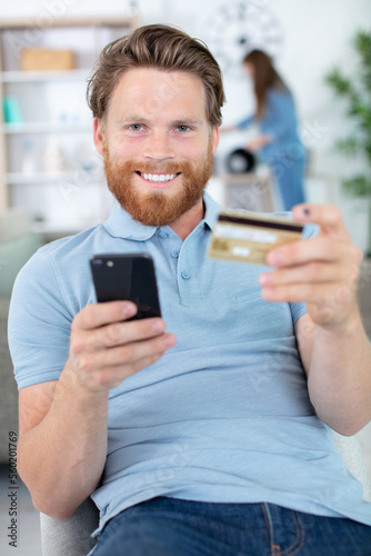 smiling man is using phone and credit card