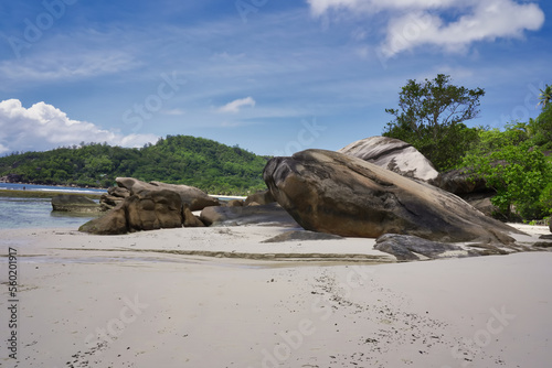 Mahe Seychelles, baie Lazare beach with rock formations and white sand. blue sky and low tide, woman posing for a picture