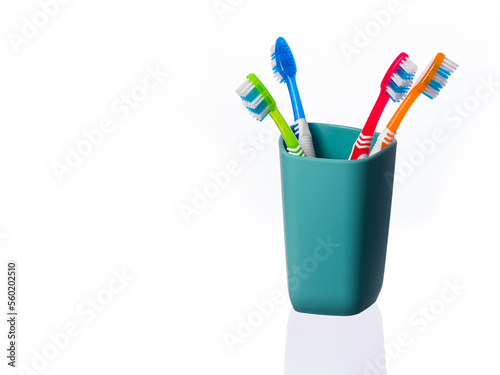 Blue  red  green and orange toothbrushes in a turquoise glass on a white background. Horizontal position of the frame. Highlighted in white. 