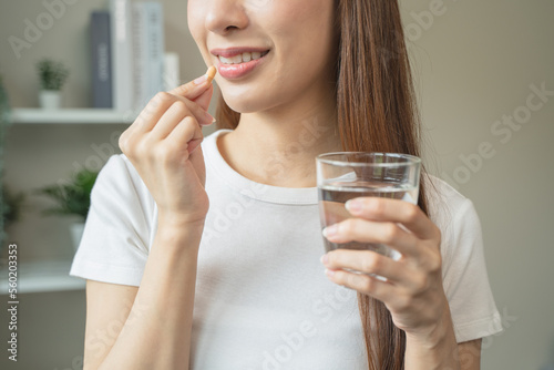 close up person taking multivitamin capsules to her mouth